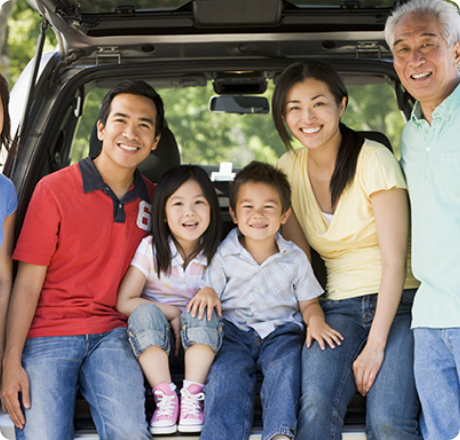 ワンボックスカーのリアゲートを開けて、大人と子供が笑顔で座っている写真